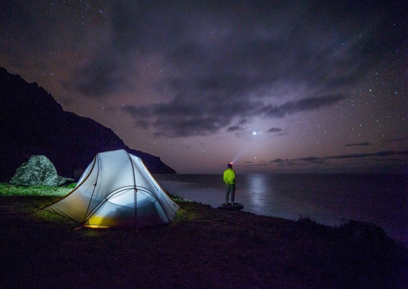 Panorama nocturne de la tente et de l'homme sur la plage