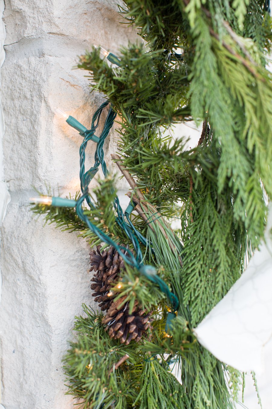 Kint karácsonyi díszek: örökzöld növények füzére, tündérfények és fenyőtobozok